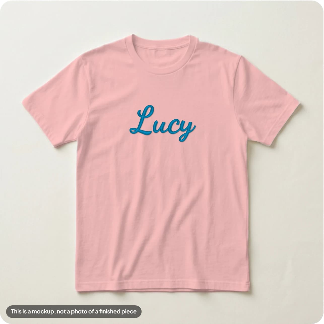A name in a joined cursive font on a washed pink tee